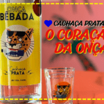 foto de uma garrafa de cachaça prata "coração da onça" com a logo da Onça Bêbada e um copo de dose ao lado