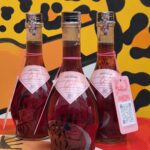 Garrafas do licor de jaboticaba "boto" posicionadas sobre uma mesa de bar com a logo da Onça Bêbada