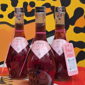 Garrafas do licor de jaboticaba "boto" posicionadas sobre uma mesa de bar com a logo da Onça Bêbada